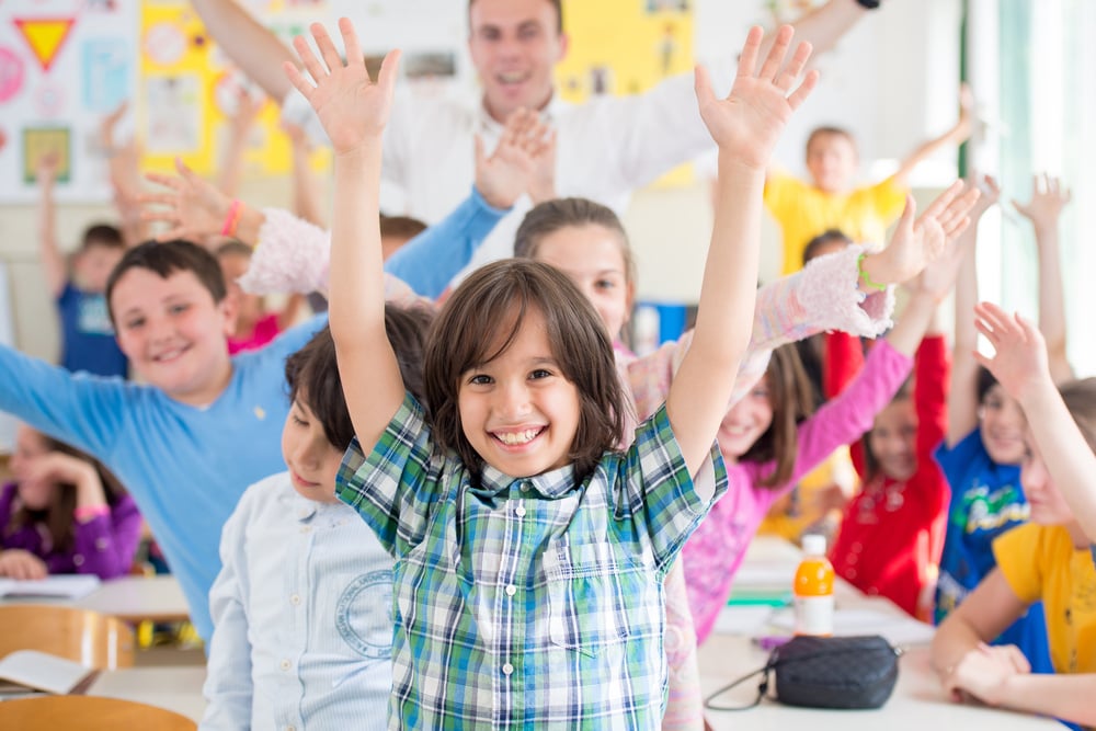 Cheerful group of kids wtih their teacher in school classroom