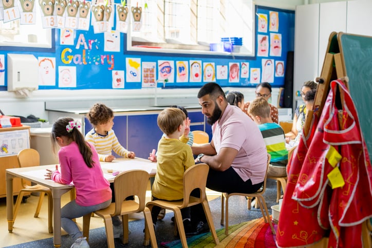 teacher speaking with student in a classroom sitting at a small table